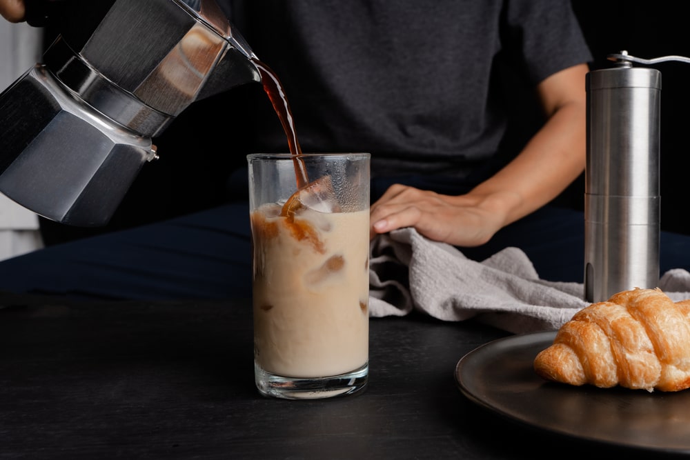 A man filling glass with cold coffee